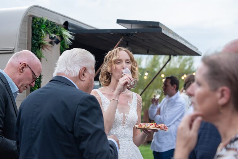 Bruid met een glas wijn en een bordje antipasti bij de Vini Vicini caravan
