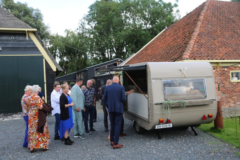 Bruiloftsgasten in de rij bij de Vini Vicini caravan op een boerderijlocatie