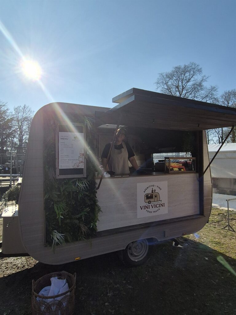 De Vini Vicini caravan met geopende luifel in de zon tijdens een feest