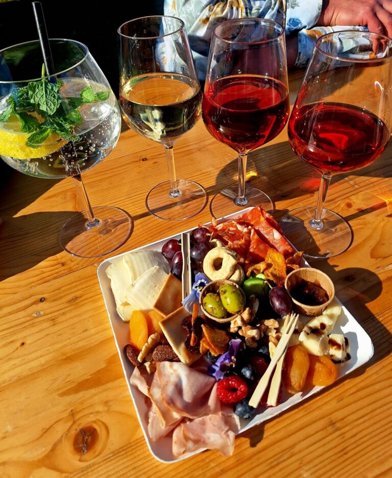 Vier glazen Italiaanse wijn naast een borrelplateau op een houten tafel