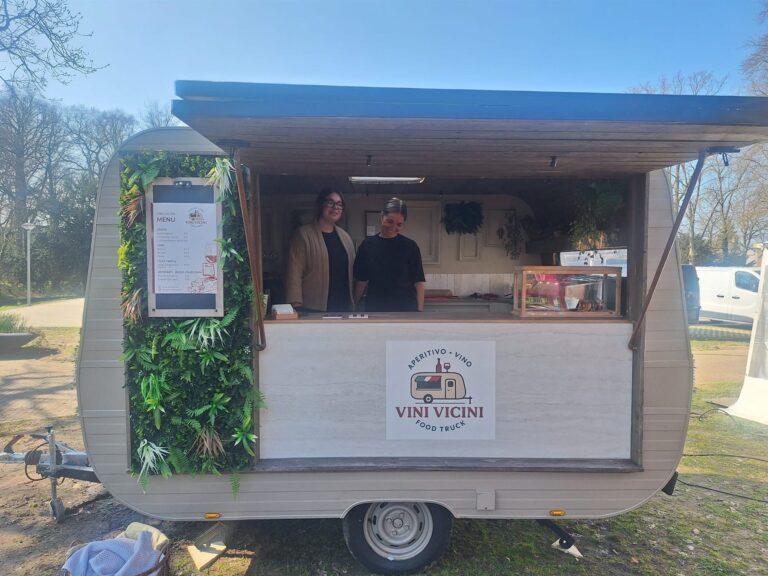 Vooraanzicht van de geopende Vini Vicini caravan met het logo op de zijkant